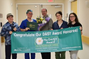 Naomi Freedberg, RN, pictured with her husband and children, accepting The DAISY Award.